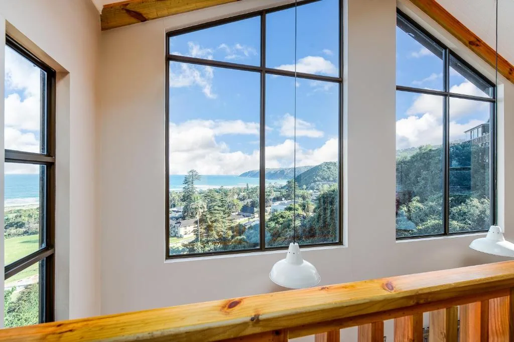 Scenic coastal landscape with mountains visible through large black-framed windows