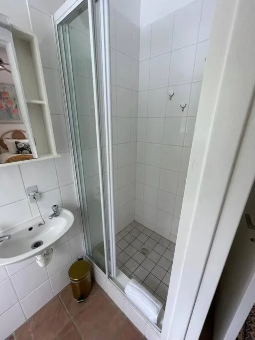 Clean bathroom with white tiles, shower enclosure, and round sink
