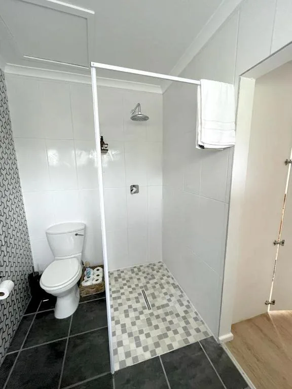 Modern bathroom with walk-in shower, toilet, and checkered floor tiles