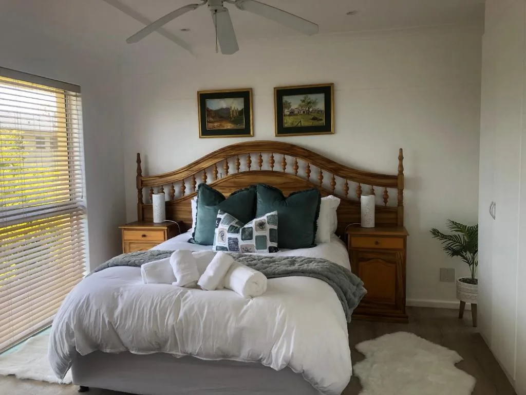 Wooden bed with white linens and decorative pillows in bright bedroom