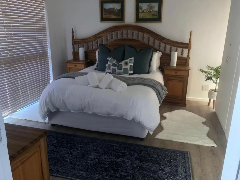 Wooden bed with white bedding and decorative pillows in bright bedroom