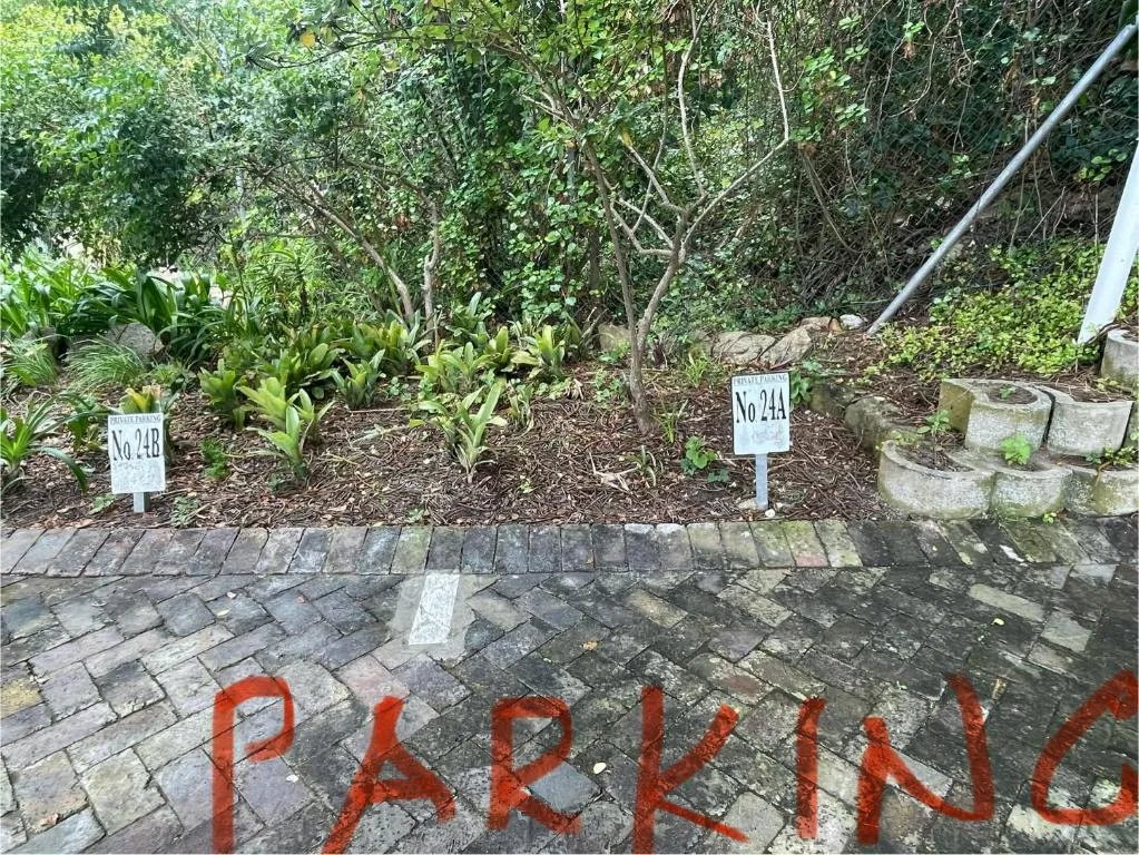Garden pathway with numbered plant markers and paved walkway surrounded by lush vegetation