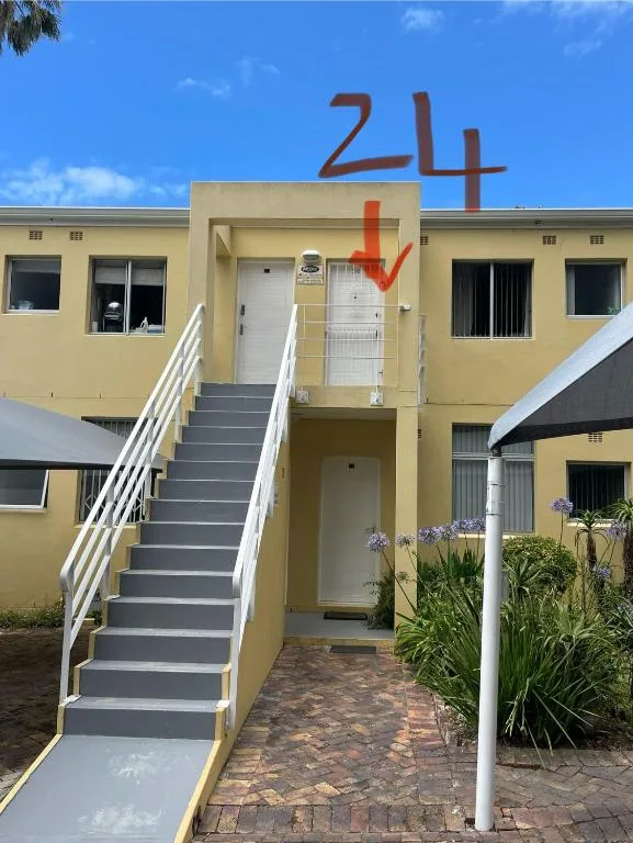 Yellow modern apartment building with white stairs and entrance numbered 24