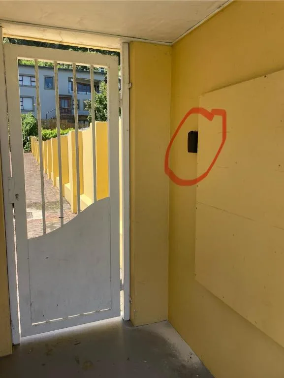 Yellow-painted entrance door with security gate opening to courtyard