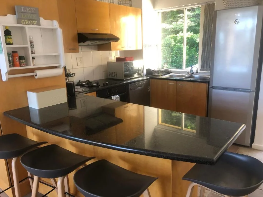 Modern kitchen with black countertops, wooden cabinetry, and breakfast bar seating