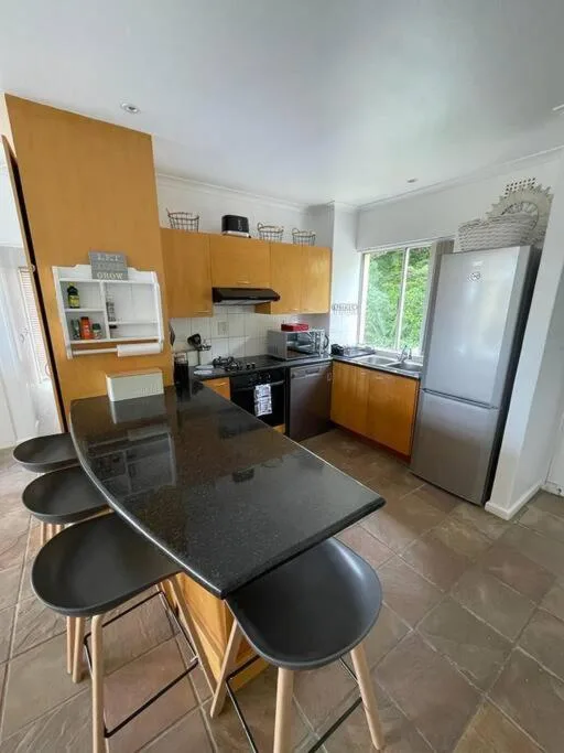 Modern kitchen with yellow cabinetry, black countertops, and dining table