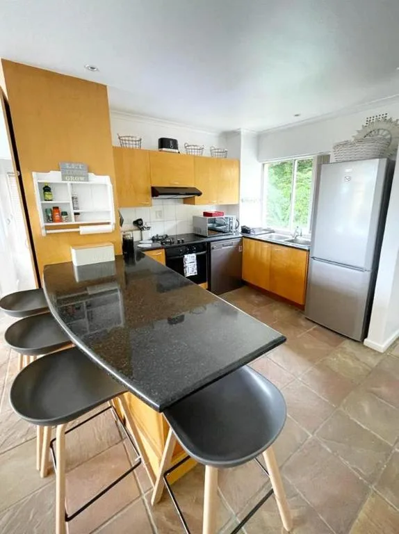 Modern kitchen with yellow cabinetry, black countertop, and dining table