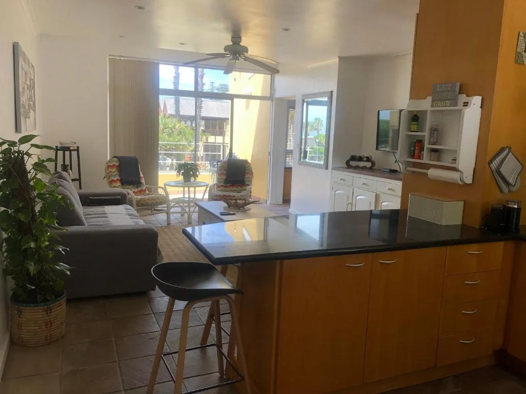 Open-plan lounge and kitchen area with sofa, black dining counter, and deck access