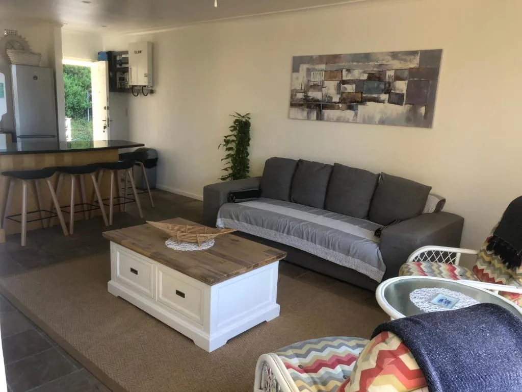 Open-plan lounge with dark grey sofa, wooden coffee table, and bar seating area