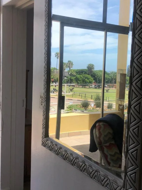 Scenic outlook from window toward green sports field and distant treeline