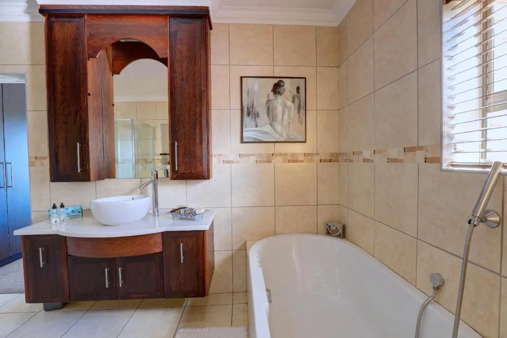 Spacious bathroom with wooden vanity, round basin, and freestanding bathtub