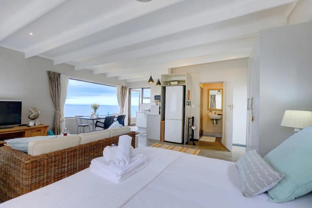Spacious bedroom with ocean view, bed, and integrated lounge area