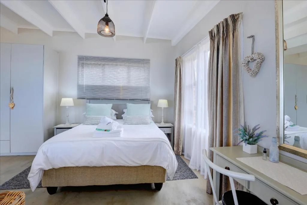 Bright bedroom with queen bed, white linens, and coastal decor