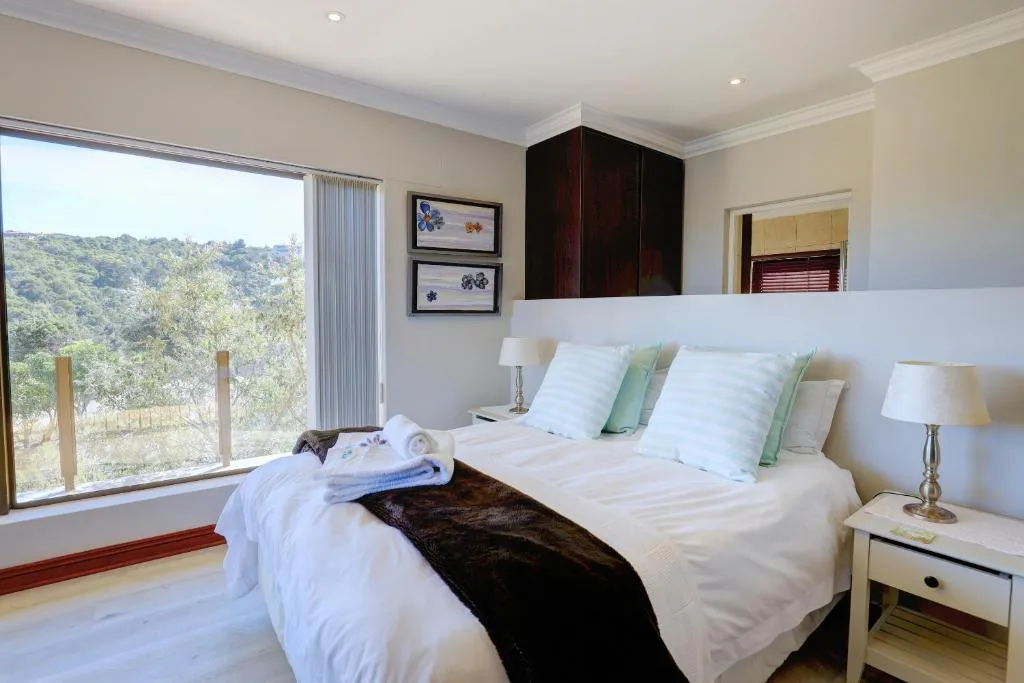 Bright bedroom with twin beds, green accents, and mountain views through large windows