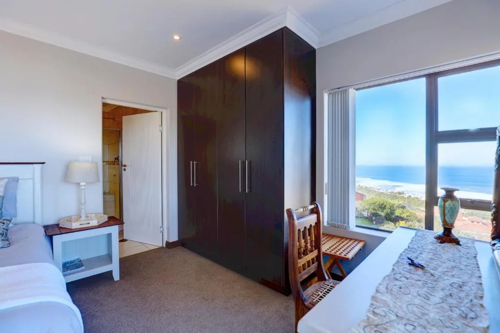 Spacious bedroom with dark wardrobe, ocean view through large windows