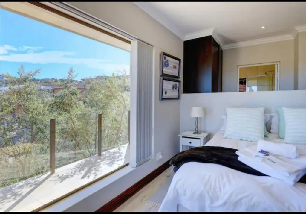Bright bedroom with double bed and scenic lagoon views through large sliding doors