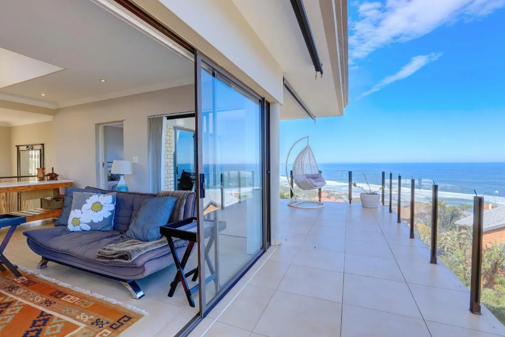 Spacious oceanfront deck with hanging chair and coastal views