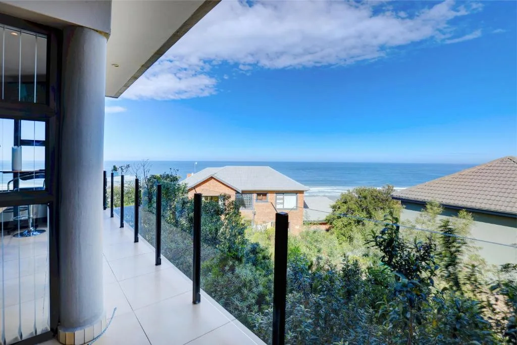 Modern balcony with ocean views, black railing, and coastal landscaping