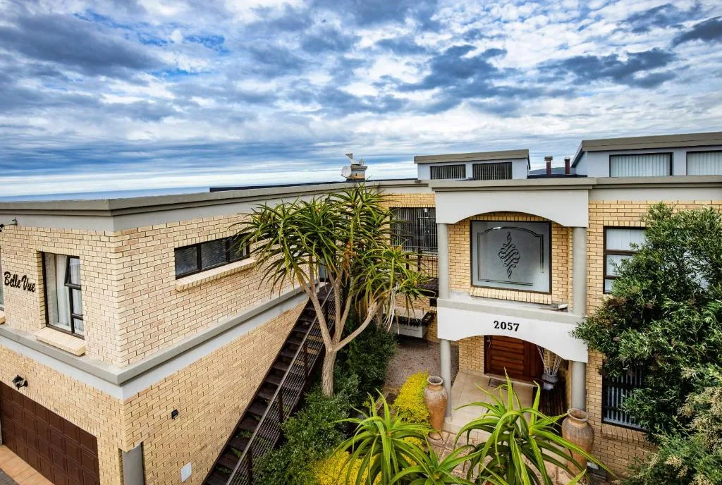 Modern brick apartment building exterior with landscaped entry garden and cloudy sky