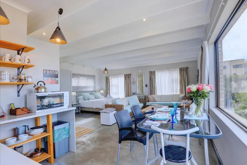 Open-plan living area with dining table, sofa, and bedroom visible in background