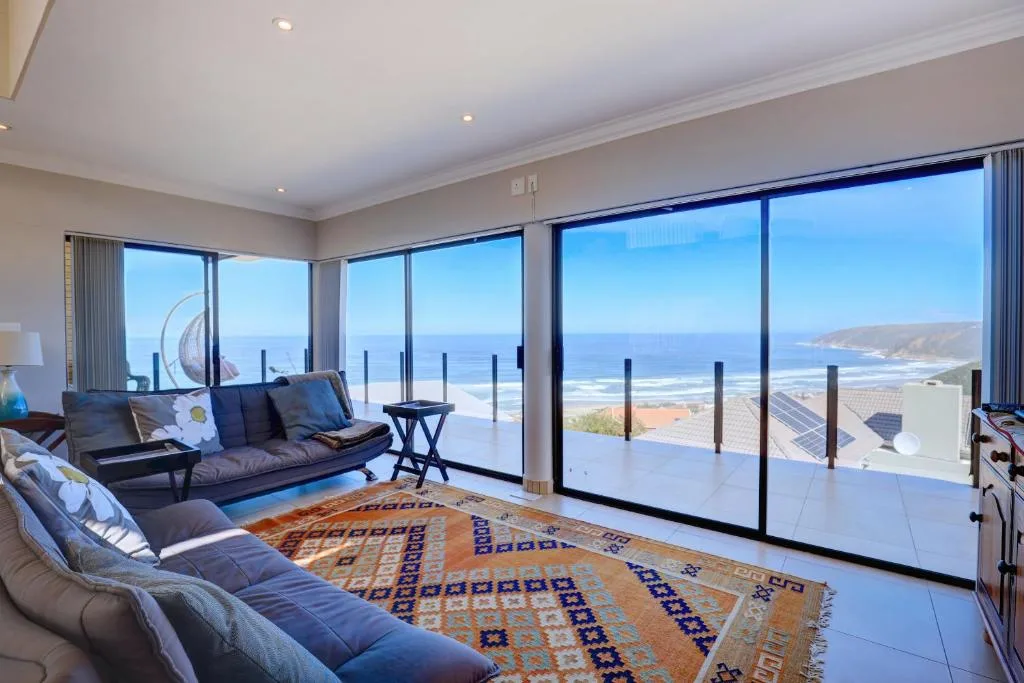 Modern lounge with blue sofa, scenic ocean and coastal views through large windows