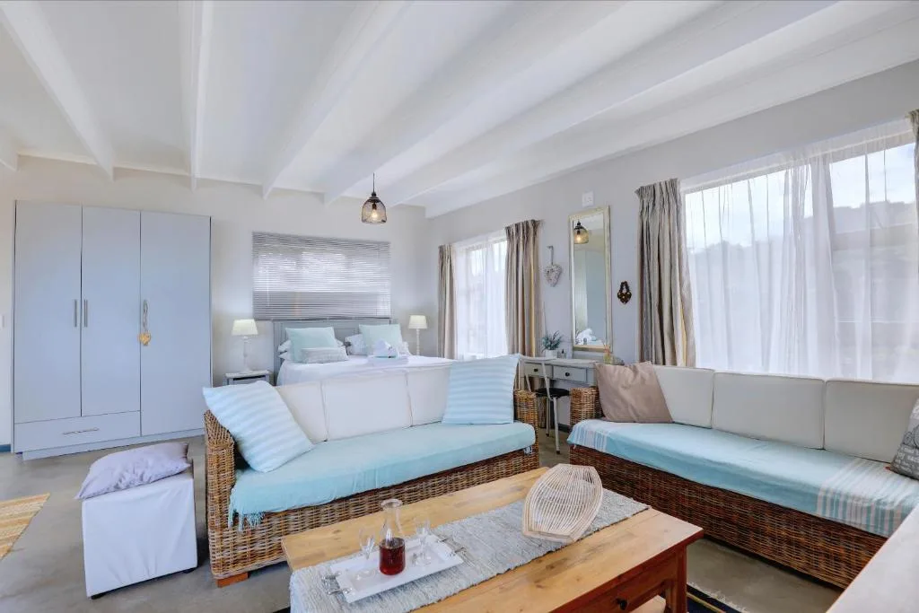 Bright studio lounge with wicker seating and queen bed visible