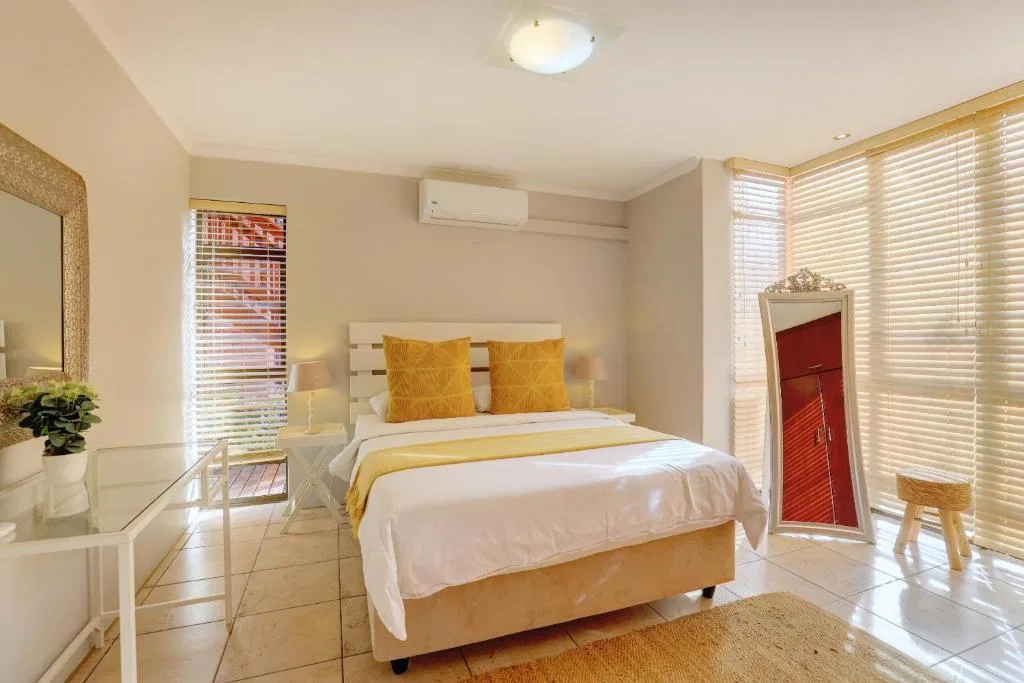 Bright bedroom with queen bed, yellow accents, and ocean view doors
