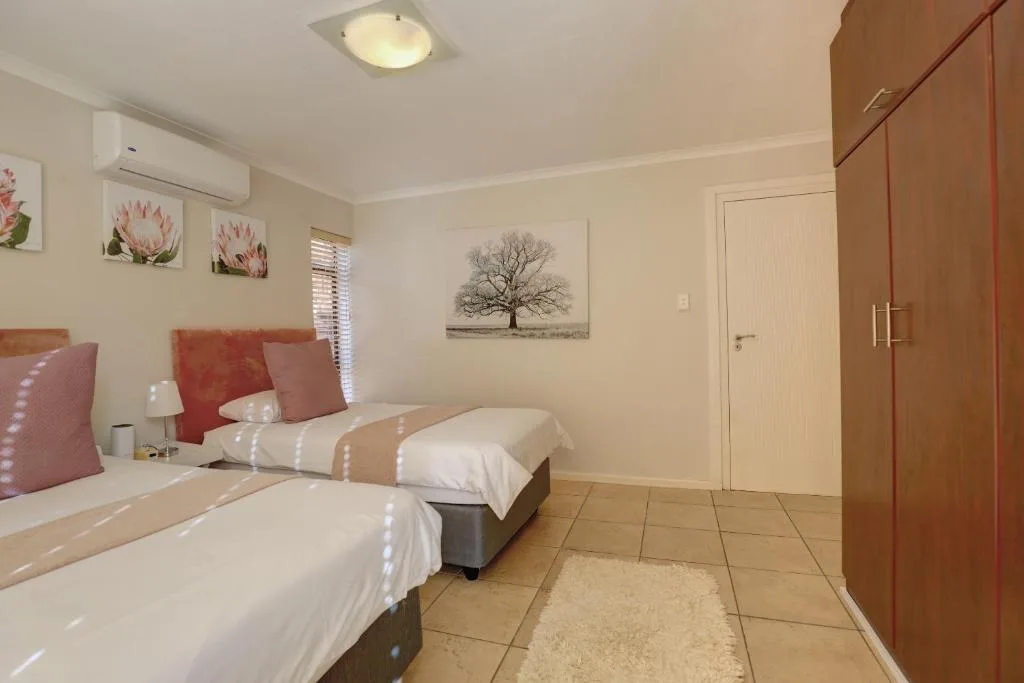 Spacious bedroom with twin beds, red cushions, and wooden wardrobe