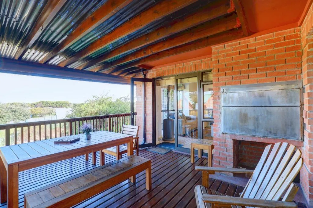 Covered deck with wooden table, chairs, and scenic lagoon views beyond.