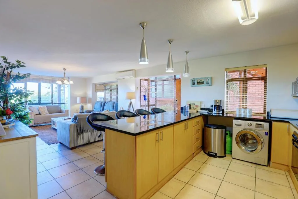 Modern kitchen with yellow cabinetry, stainless steel appliances, and open-plan living area