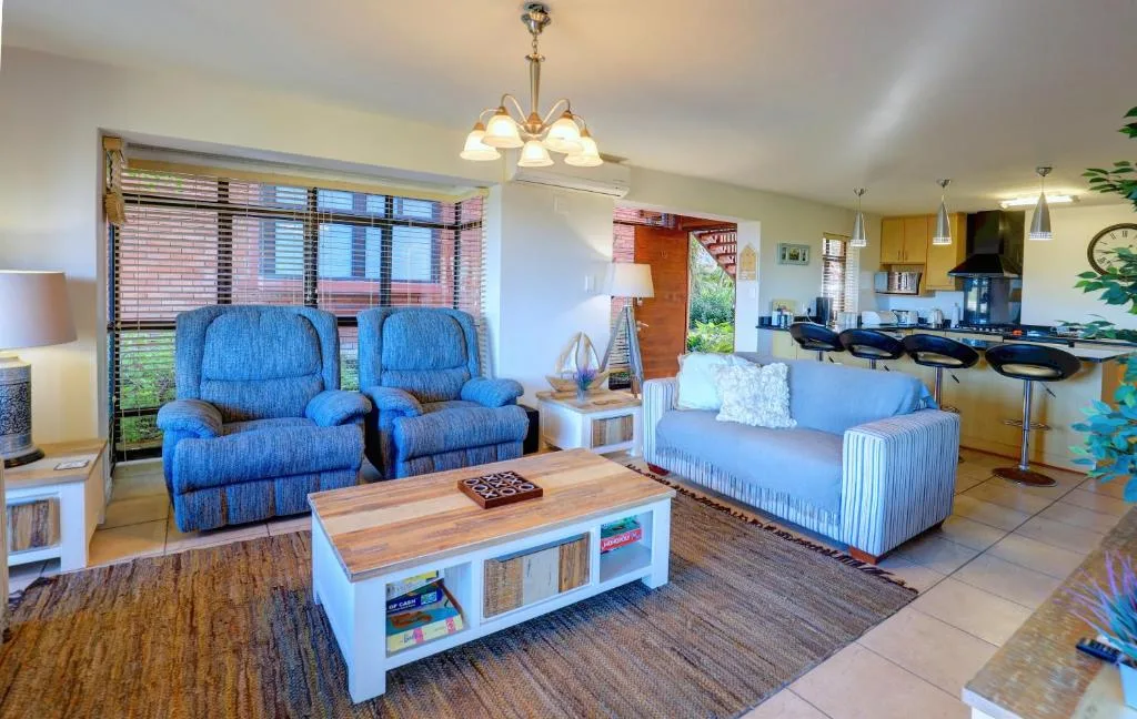 Spacious lounge with blue recliners, striped sofa, and open-plan kitchen view