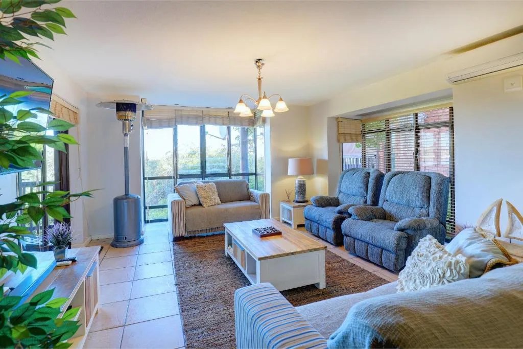 Spacious lounge with blue recliners, comfortable sofas, and ocean views through large windows