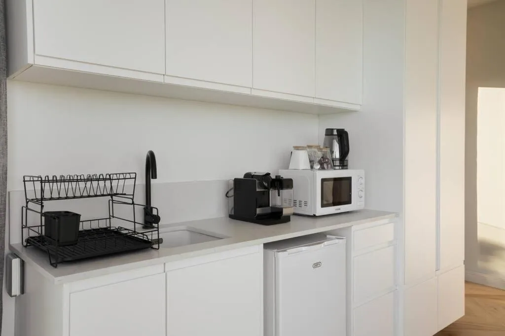 Modern white kitchen with countertops, microwave, kettle, and compact appliances