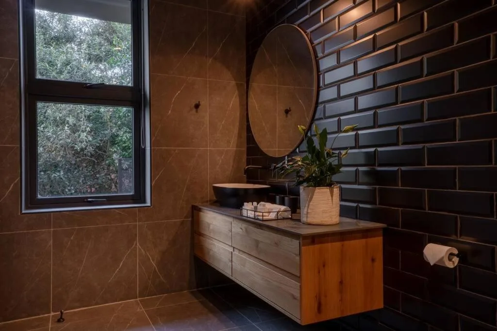 Modern bathroom with floating vanity, round mirror, and black brick accent wall