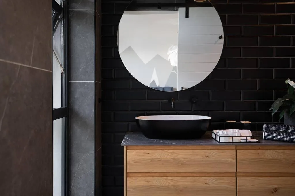 Modern bathroom with black vessel sink and round mirror reflecting mountains