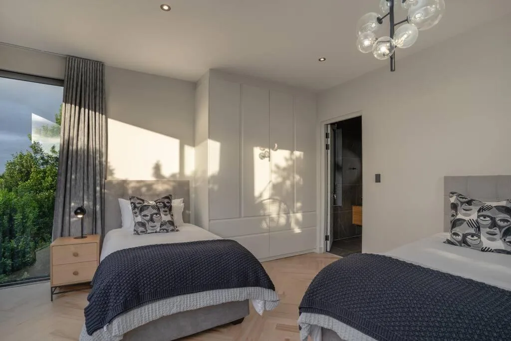 Modern twin bedroom with built-in wardrobes and natural light from large windows
