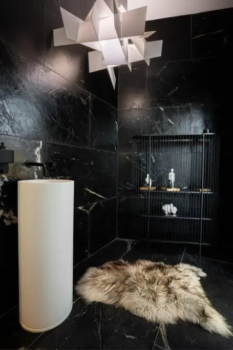 Modern interior with geometric pendant light, marble walls, and decorative accessories