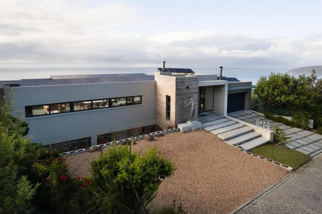 Modern white house with wooden accents and coastal mountain views behind