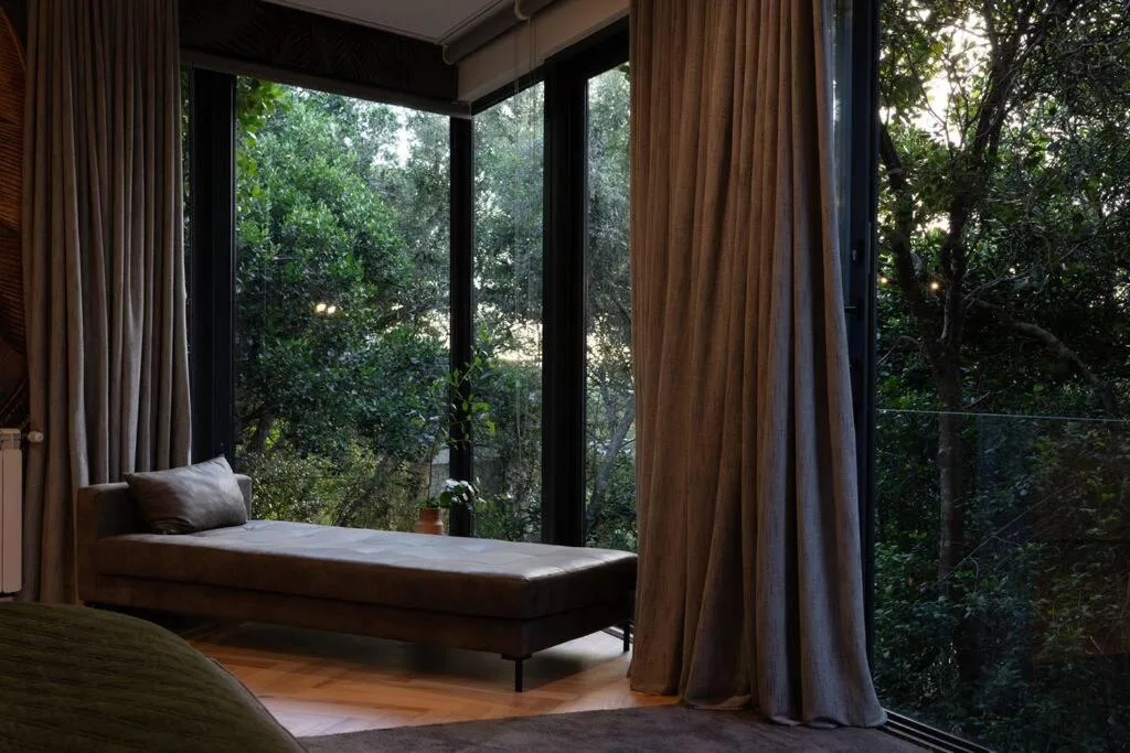 Modern lounge with daybed seating and expansive forest views through large windows