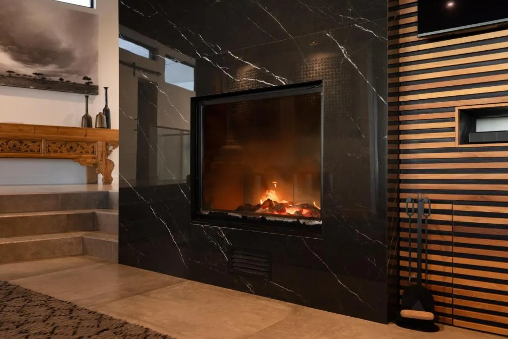 Modern lounge with black marble fireplace and wooden accent wall