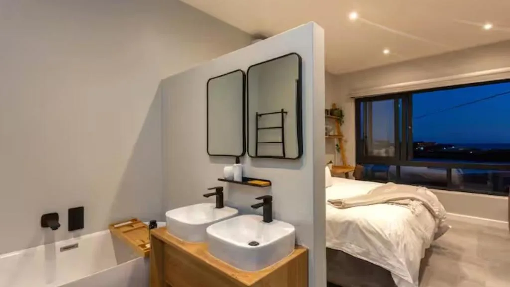 Modern ensuite bathroom with dual vanity sinks and large mirrors in bedroom