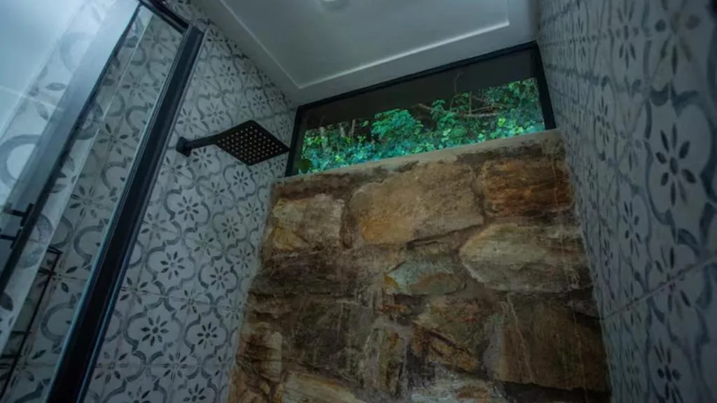 Modern bathroom with patterned tiles, rainfall showerhead, and stone accent wall