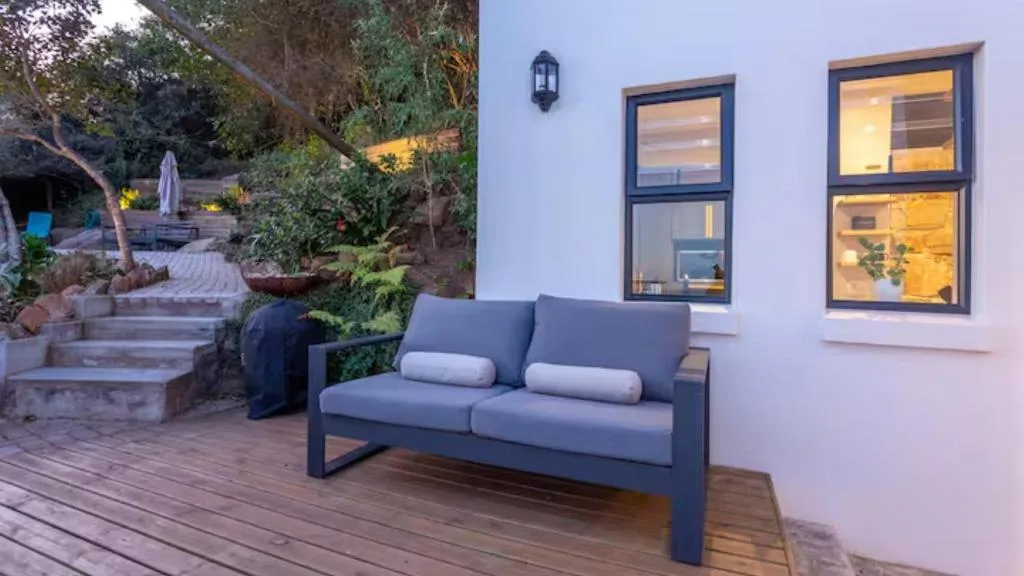 Modern outdoor seating area with gray sofa on wooden deck at dusk