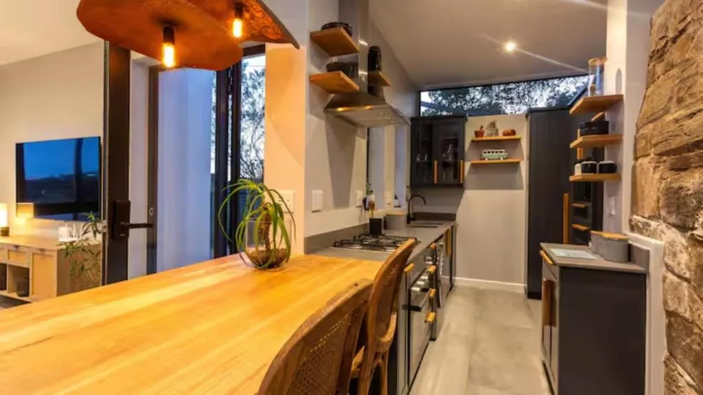 Modern kitchen with wooden counter, gas stove, and open shelving at dusk