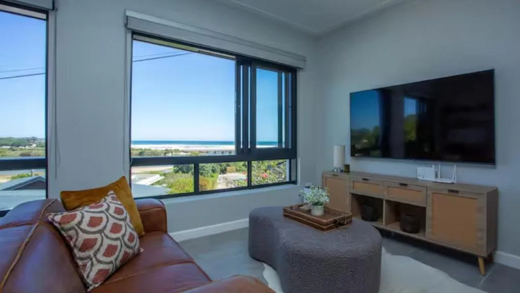 Modern living room with sofa, TV, and expansive ocean and lagoon views