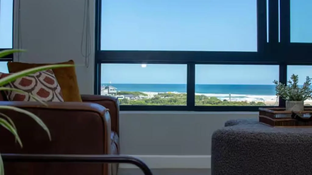 Modern lounge with coastal ocean and beach views through large windows