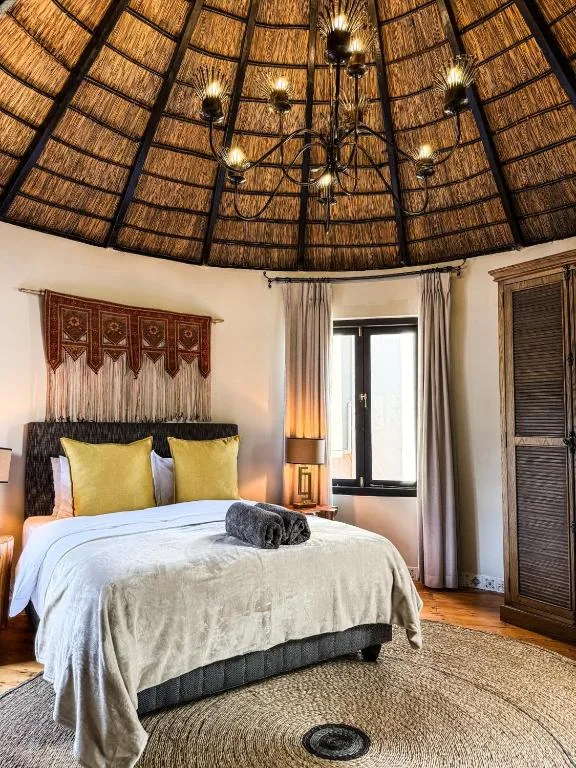 Spacious bedroom with thatched dome ceiling, queen bed, and yellow accent pillows