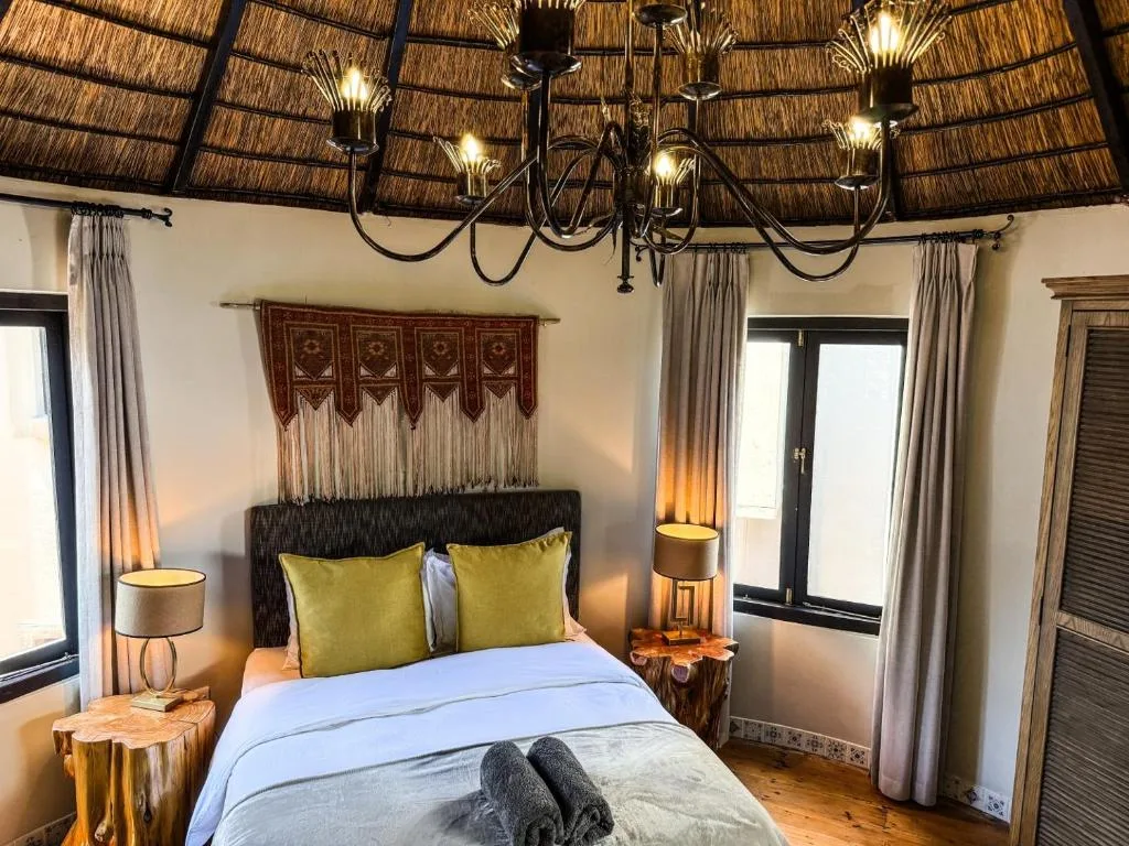 Spacious bedroom with thatched ceiling, queen bed, and warm lighting