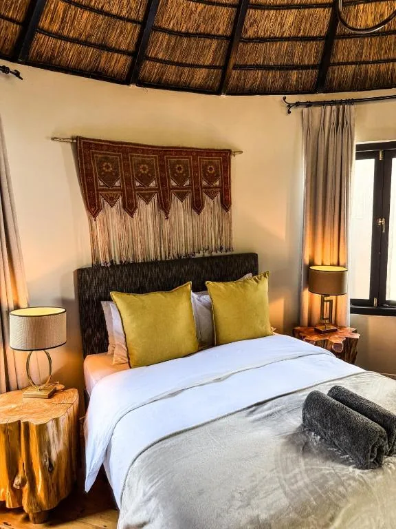 Bedroom with queen bed, yellow pillows, macramé wall hanging, thatched ceiling