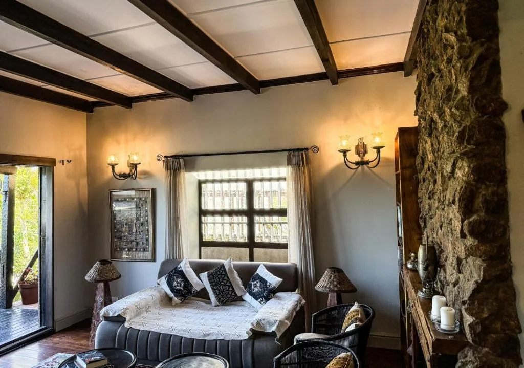 Spacious bedroom with upholstered bed, exposed stone wall, and wooden beams